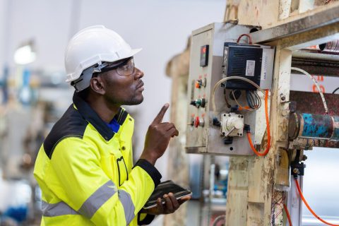 african-male-engineer-department-head-point-electronic-circuit-board-machinery-plastic-steel-industries-wear-safety-helmet-vest-holding-laptop-work_1339901-4490