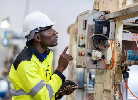 african-male-engineer-department-head-point-electronic-circuit-board-machinery-plastic-steel-industries-wear-safety-helmet-vest-holding-laptop-work_1339901-4490