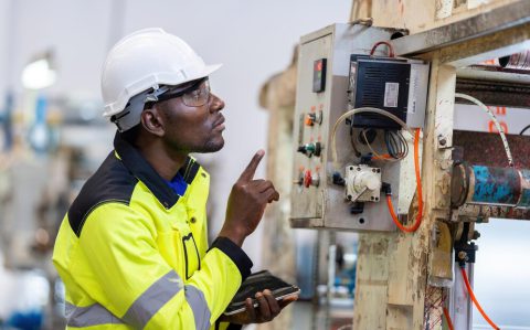african-male-engineer-department-head-point-electronic-circuit-board-machinery-plastic-steel-industries-wear-safety-helmet-vest-holding-laptop-work_1339901-4490